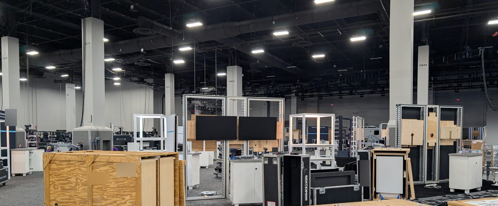 Convention center expo hall during load-in with LED displays and road cases